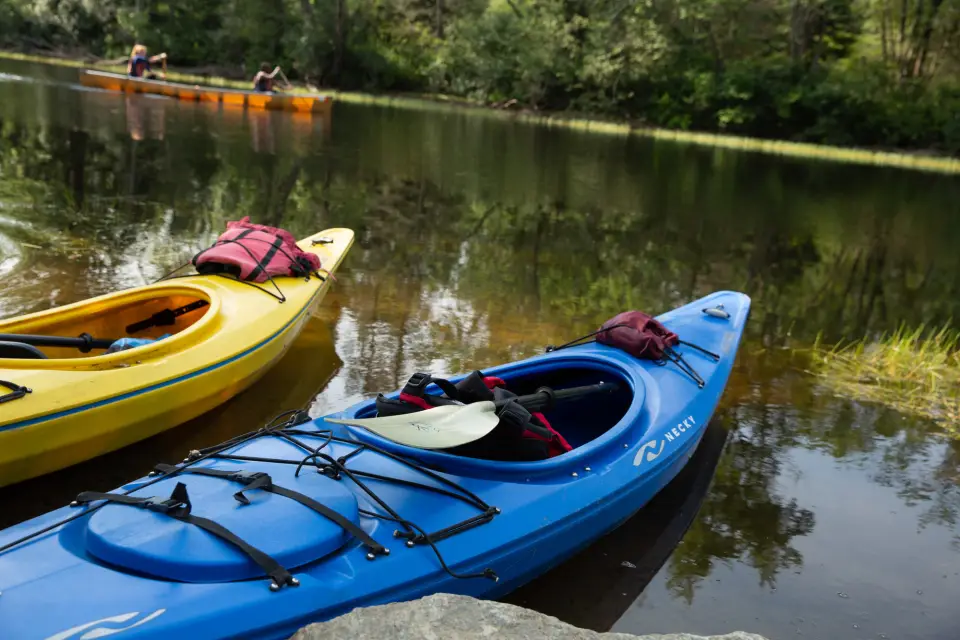 Two kayaks sit in still water.