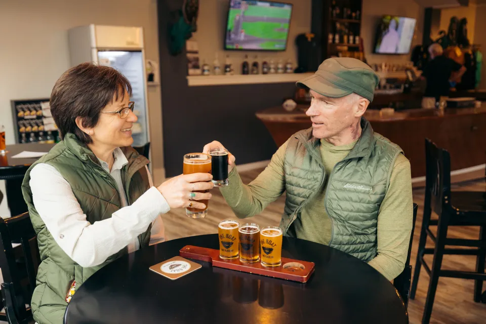 A man and woman share a flight of beers at a brewery. 