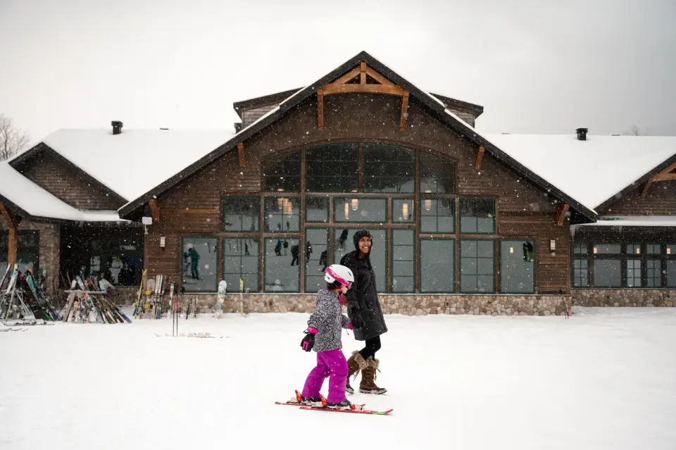 A child skiing in front of Bear Den Lodge.
