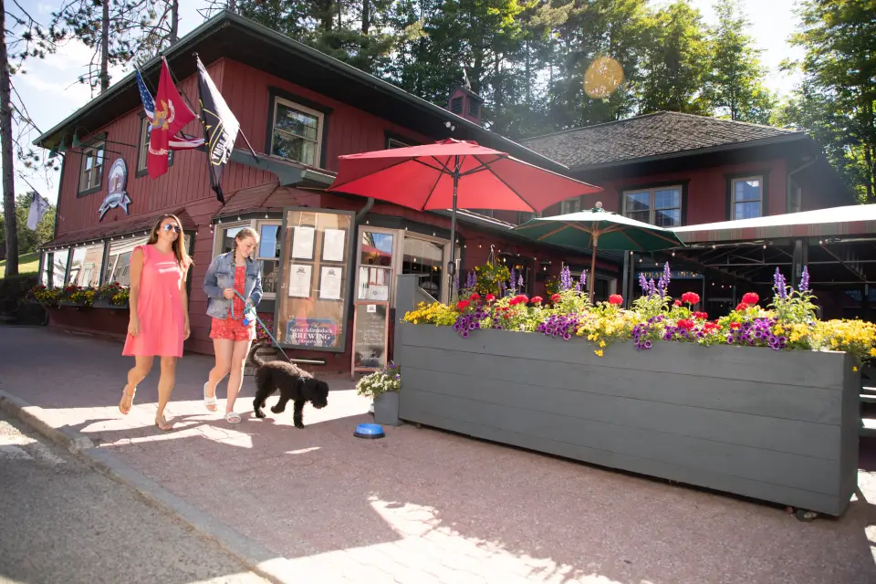 Two women walk with a dog past a restaurant on Main Street. 
