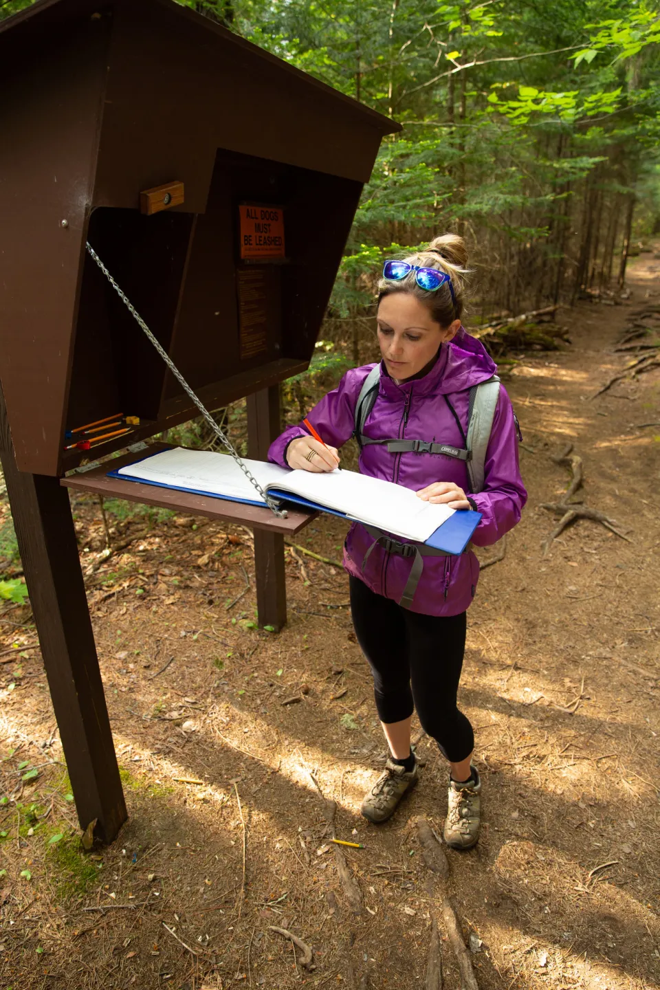 A hiker signing in at a trailhead.