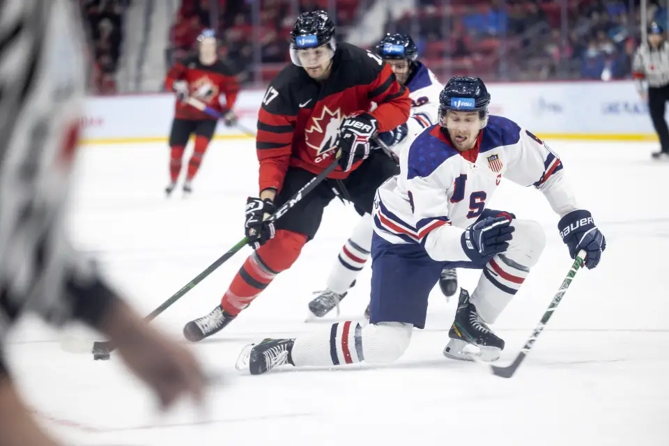 Two male hockey players fight for control of the puck at an international competition.