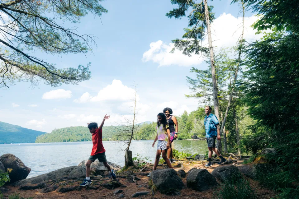 A family of four hikes on a path next to a lake. 