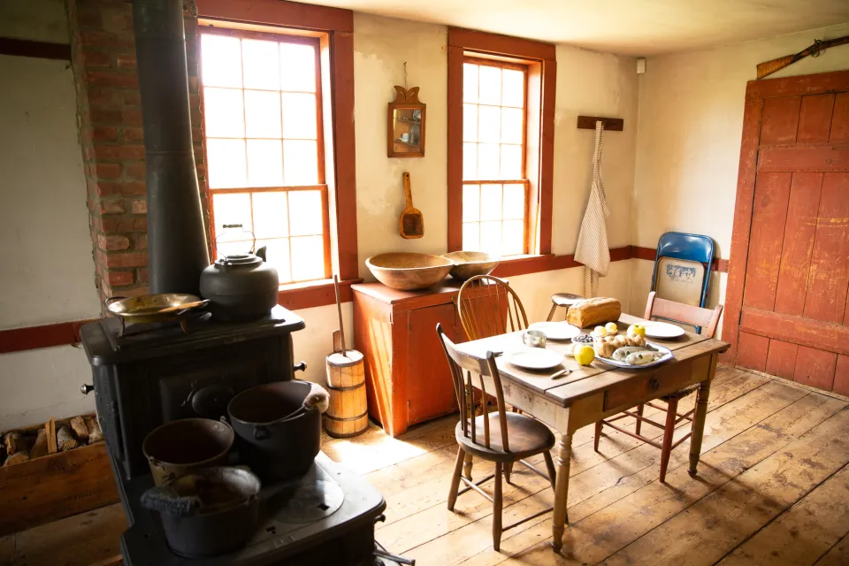 The interior of a rustic 19th-century kitchen in a historic house museum.