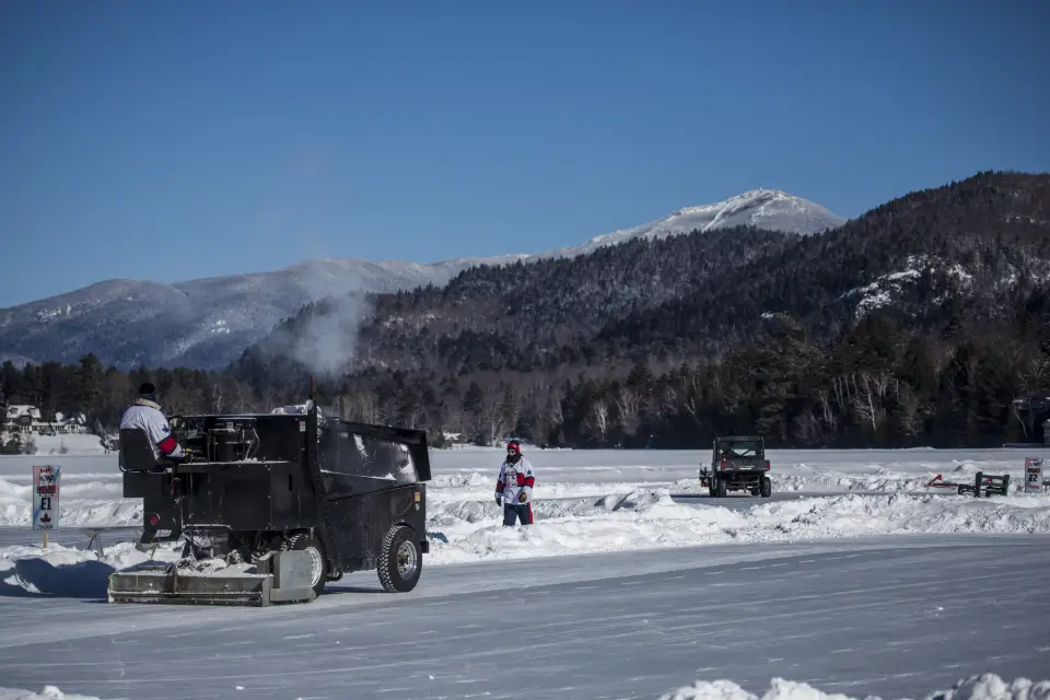 A crew of people use machines to prepare pond hockey rinks on Mirror Lake.