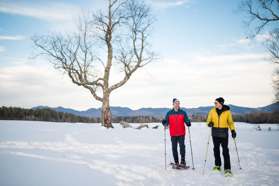 Two men snowshoeing in a snowy field.