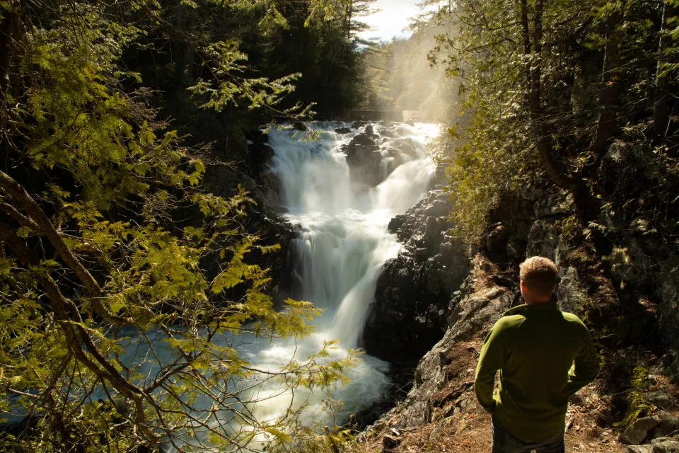 A hiker looks at a large waterfall
