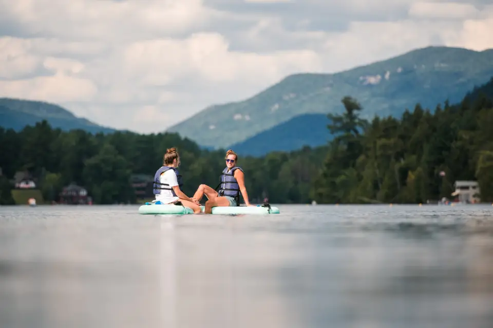 Two people sitting on paddleboards on a calm lake.