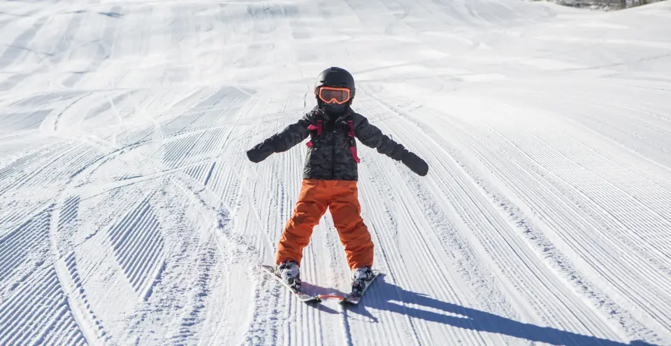 A small child skiing down a groomed trail at Mt. Pisgah Mountain.