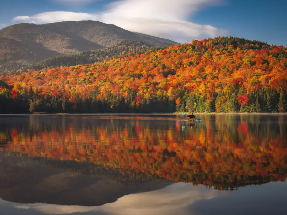 A canoe on a serene lake with beautiful fall foliage