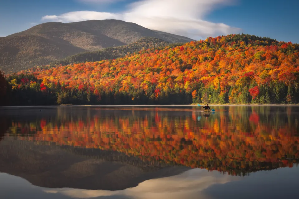 View of Heart Lake with fall foliage on mountains along shore and reflection in water