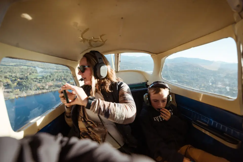 A woman and child look out the window of a small plane