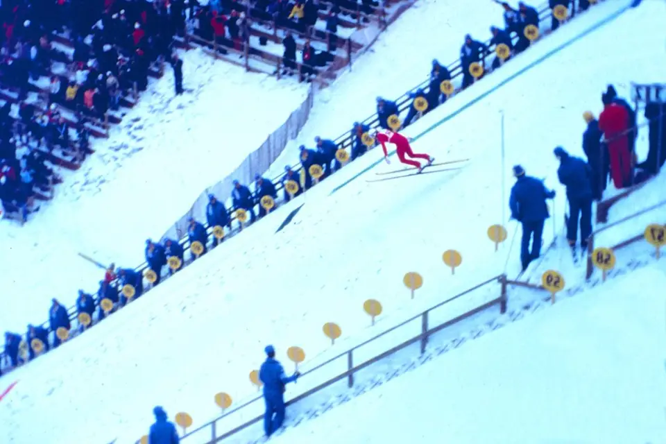 A ski jumper lands on a snowy slope in a vintage color photo from the 1980 Olympic Winter Games.