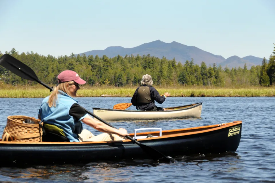 Two people paddling solo canoes during the spring.