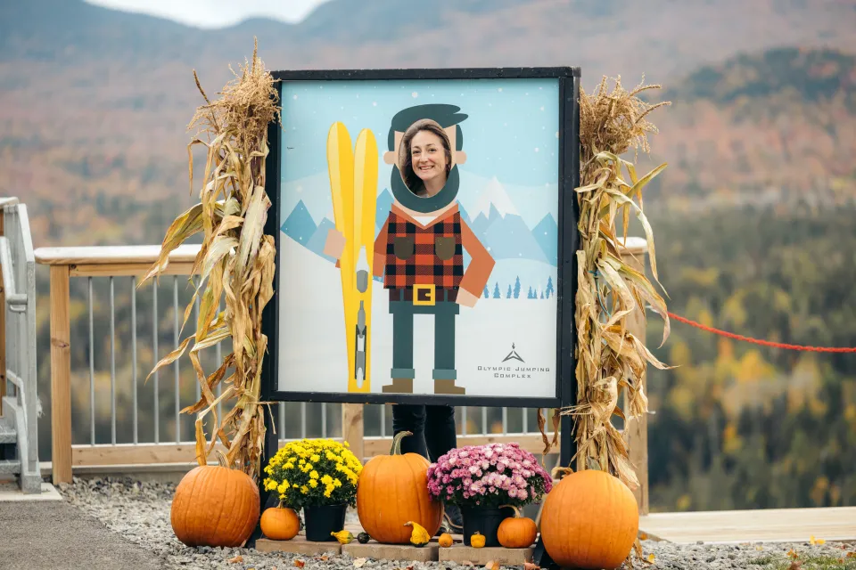 A woman poses in a frame for a fall festival.