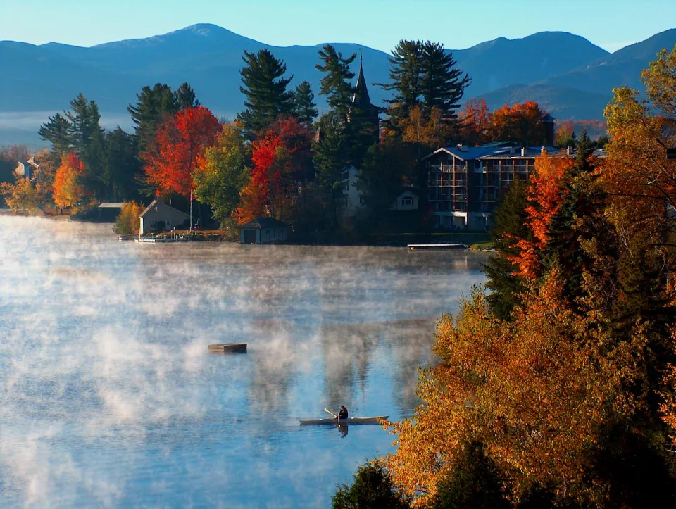 A person canoeing on the shore of Mirror Lake with stunning fall scenery.