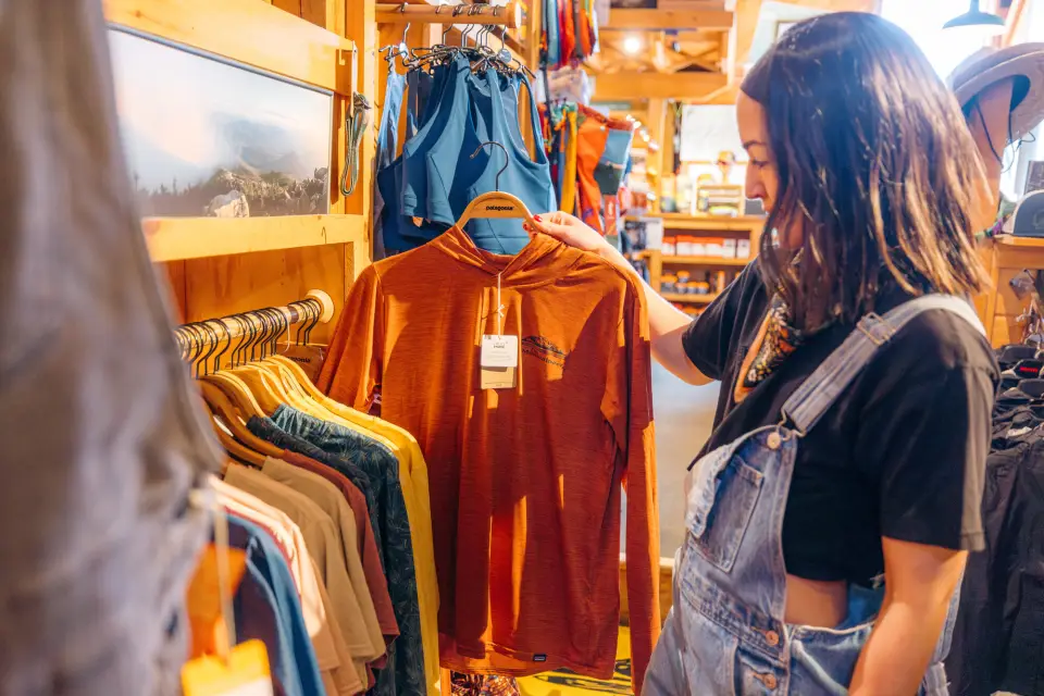 A woman holds up a shirt to purchase off the rack. 