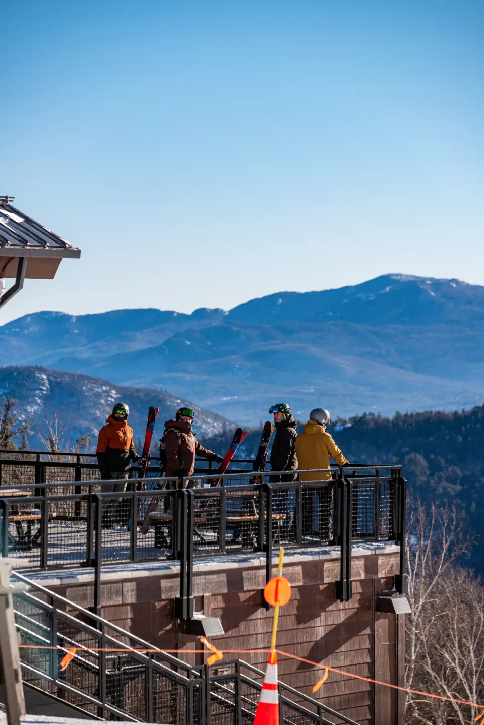 Skiers look out to a mountain range.