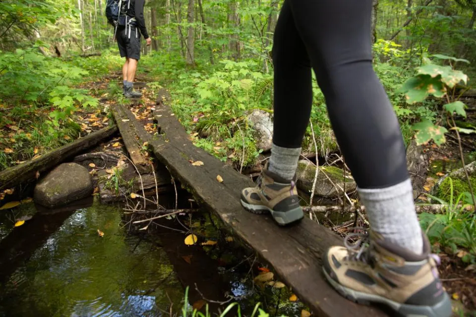 Two people walk across a wood plank