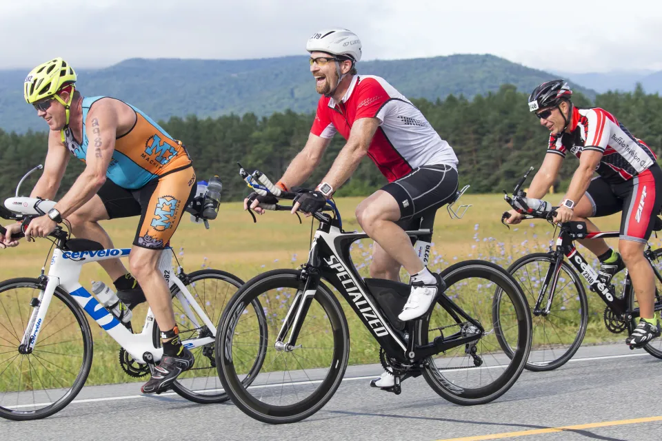 Three men cycle on a road in the High Peaks region. 