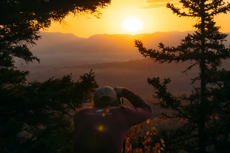 A hiker takes a photo during a sunrise in the fall