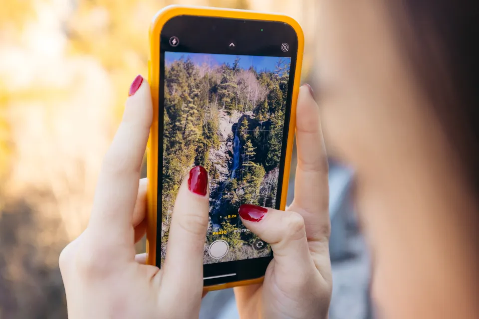 A person taking a photo of a waterfall.