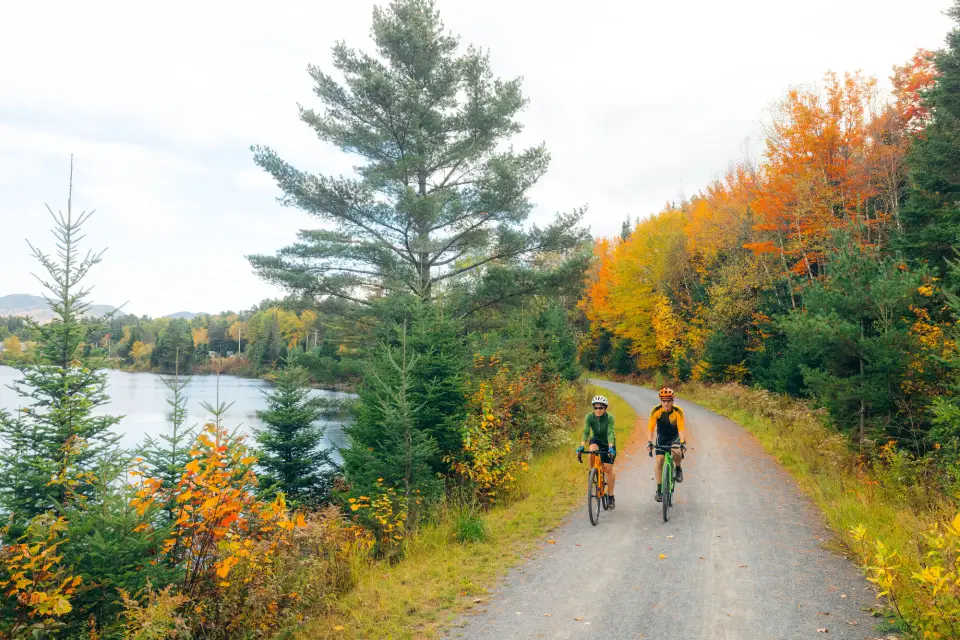 Two people biking on the Adirondack Rail Trail in the fall.