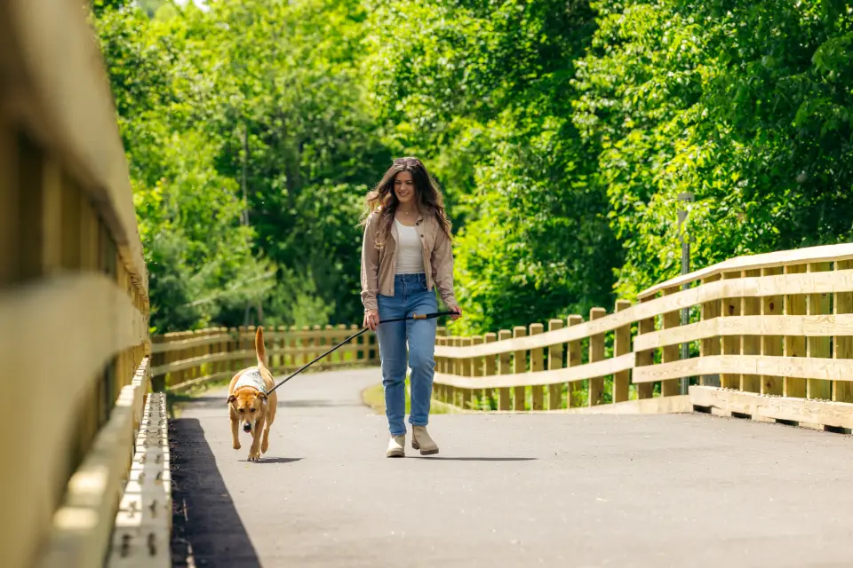 A woman walking her dog on the Adirondack Rail Trail.