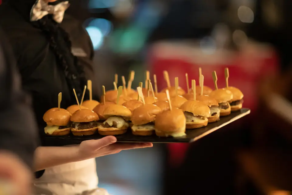 a server holds a plate of sliders.