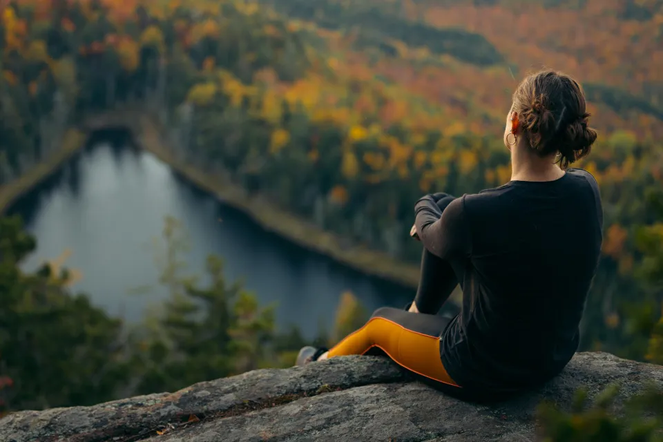 A woman sitting at the summit of a fall hike.