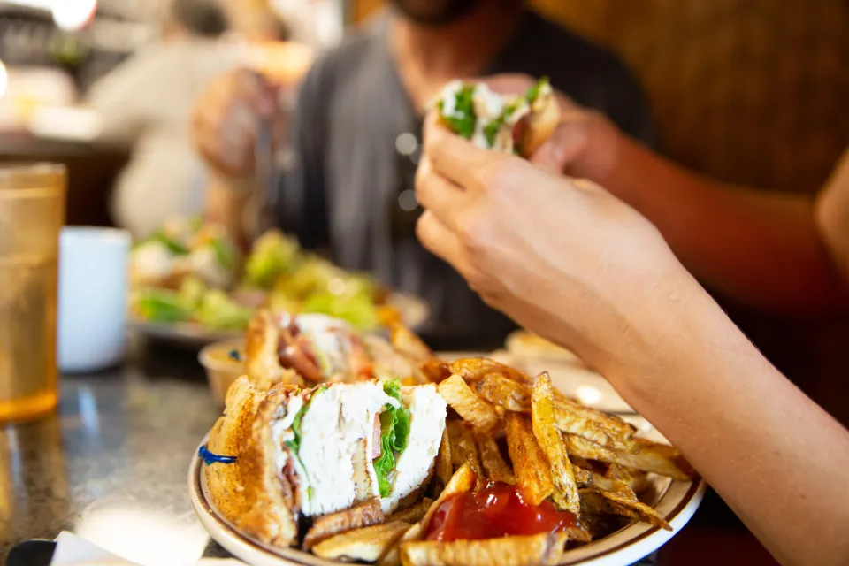 A person takes a bite out of a club sandwich. 