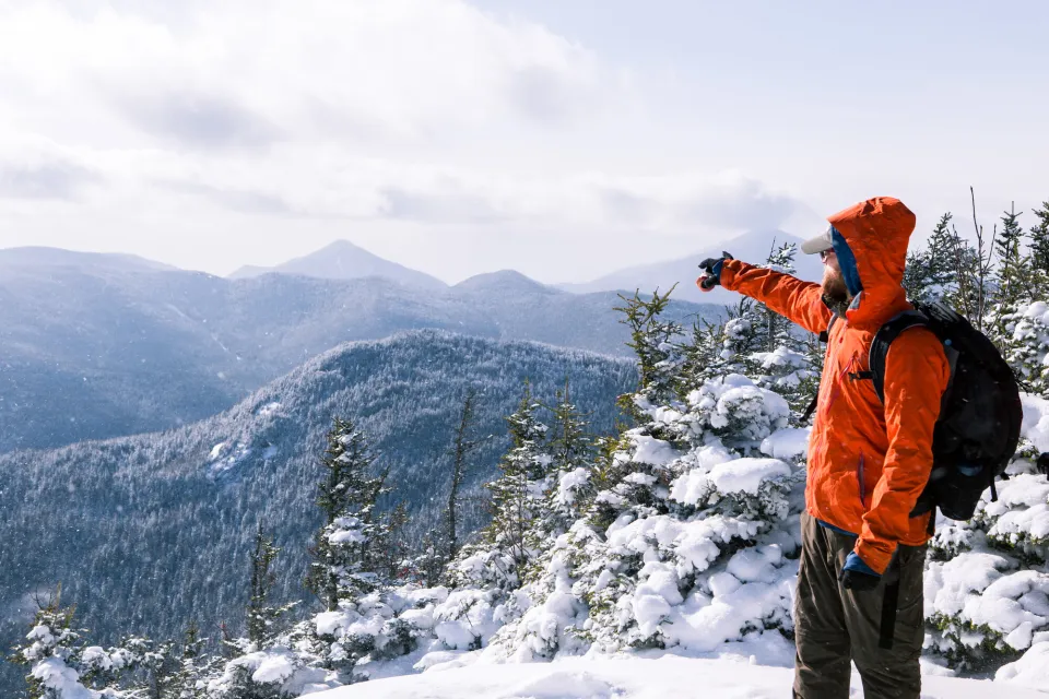 A man points to a snowy mountain scape. 