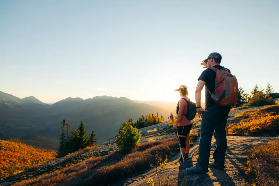 A man and woman stand on top of a mountain in fall.
