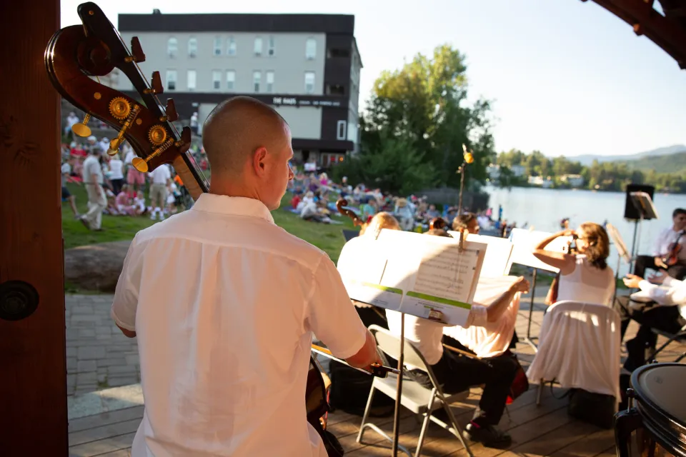 Man seen from behind playing stand-up bass in outdoor music venue