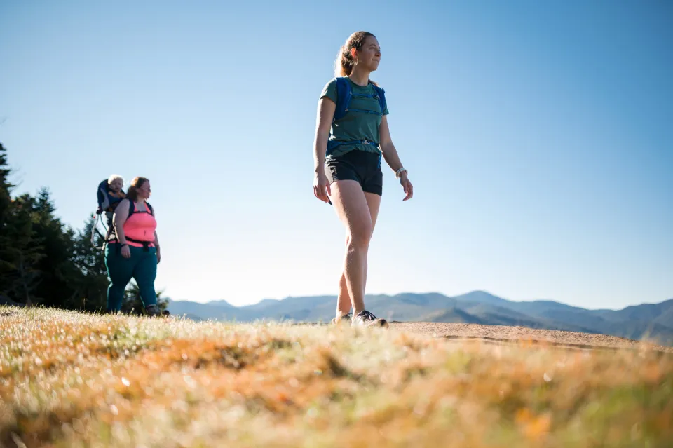 two women walk on top of a mountain.