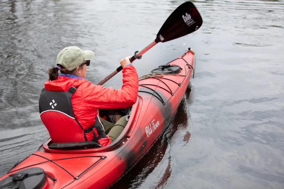 A kayaker on the water wearing layers for spring weather.