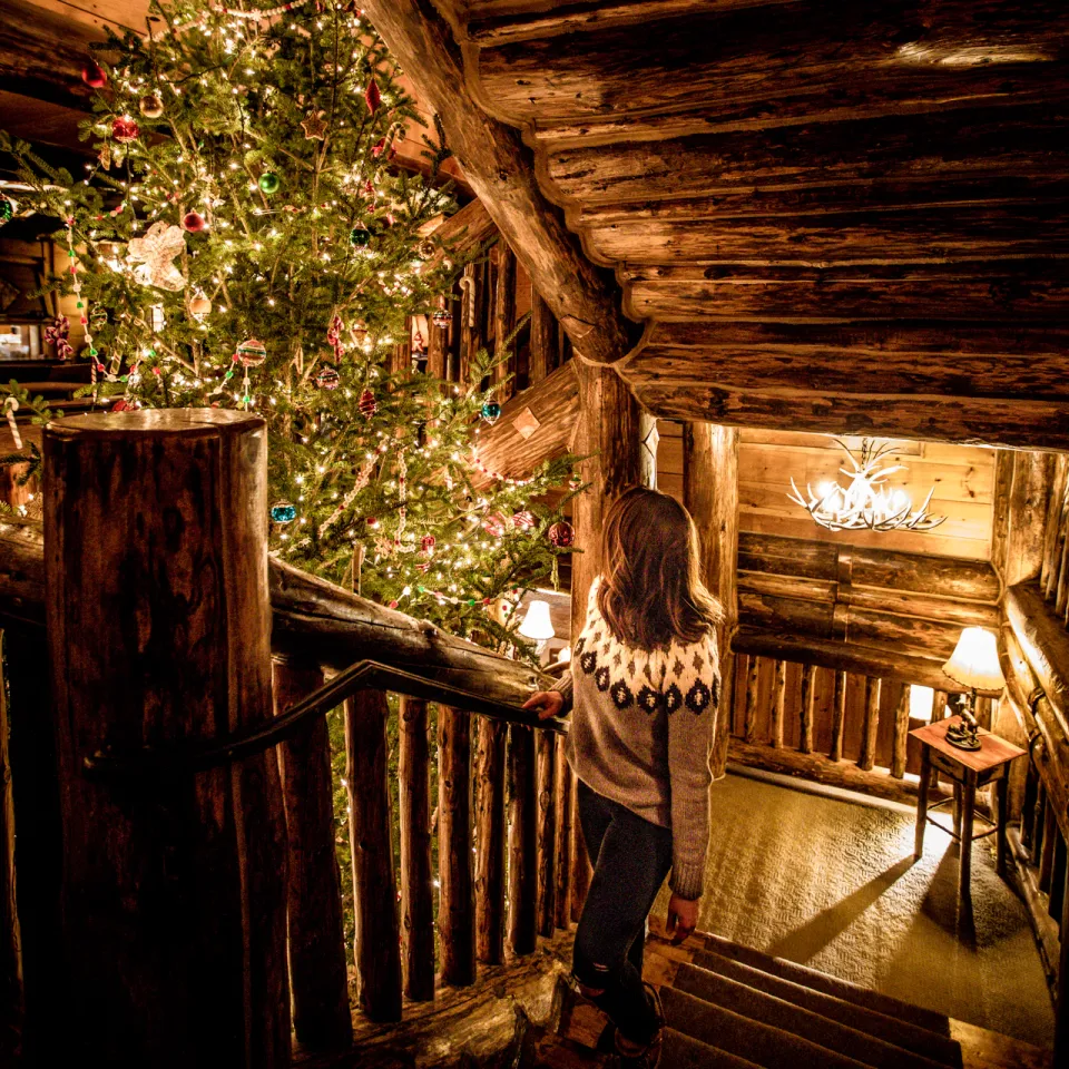 A woman walks up the stairs of a grand lodge around Christmas time.