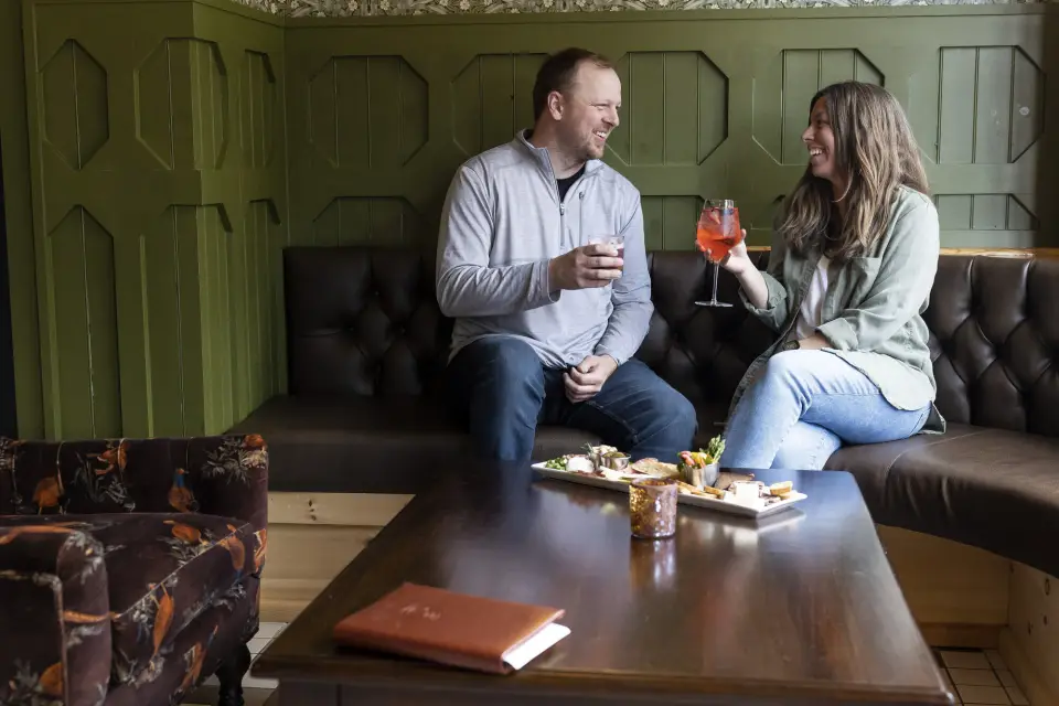 A man and woman share drinks and a charcuterie board.