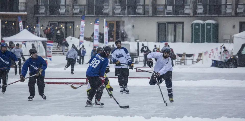 A pond hockey tournament fills several small rinks on a frozen lake.
