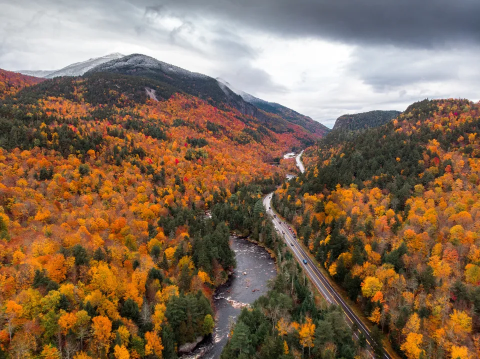 A road cuts through a fall mountain range on a cloudy day. 
