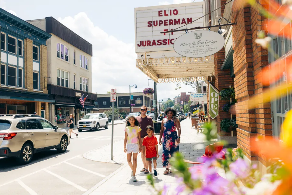 A family of four walks on a main street with a movie theater strand above them.