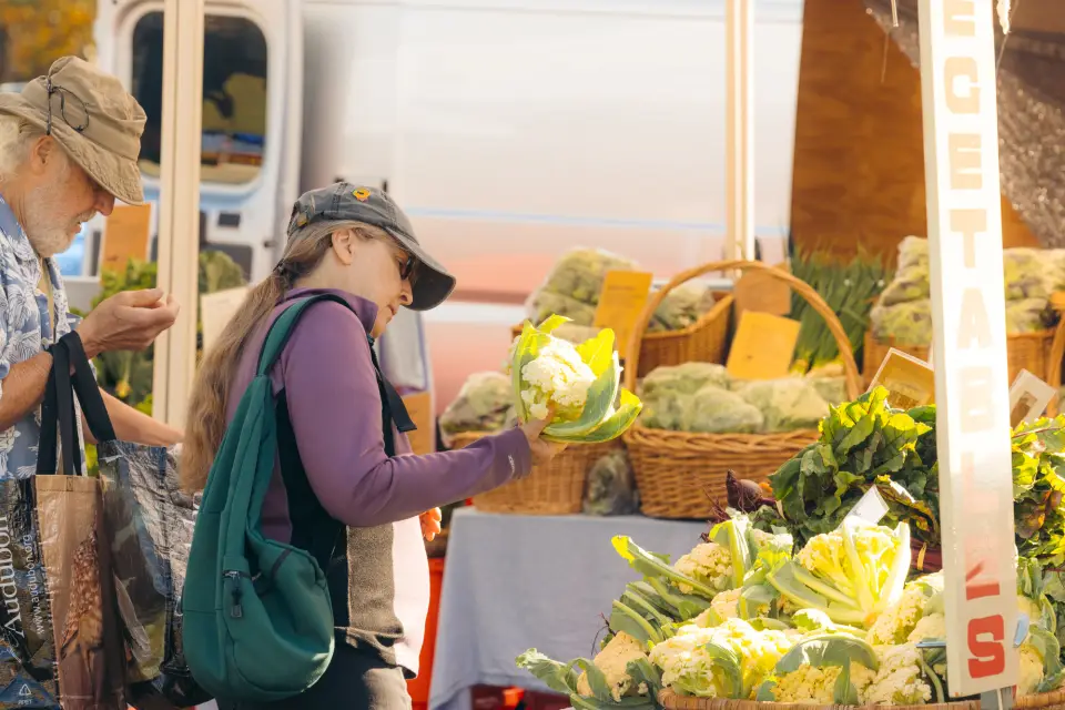 A couple looking at fresh produce at a Lake Placid farmers market.