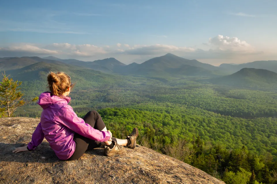 A woman sitting at the summit of a spring hike.