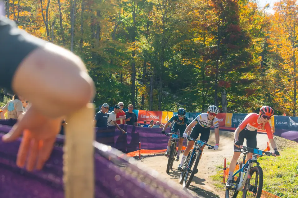 Mountain bike competitors seen racing on course through a crowd of spectators