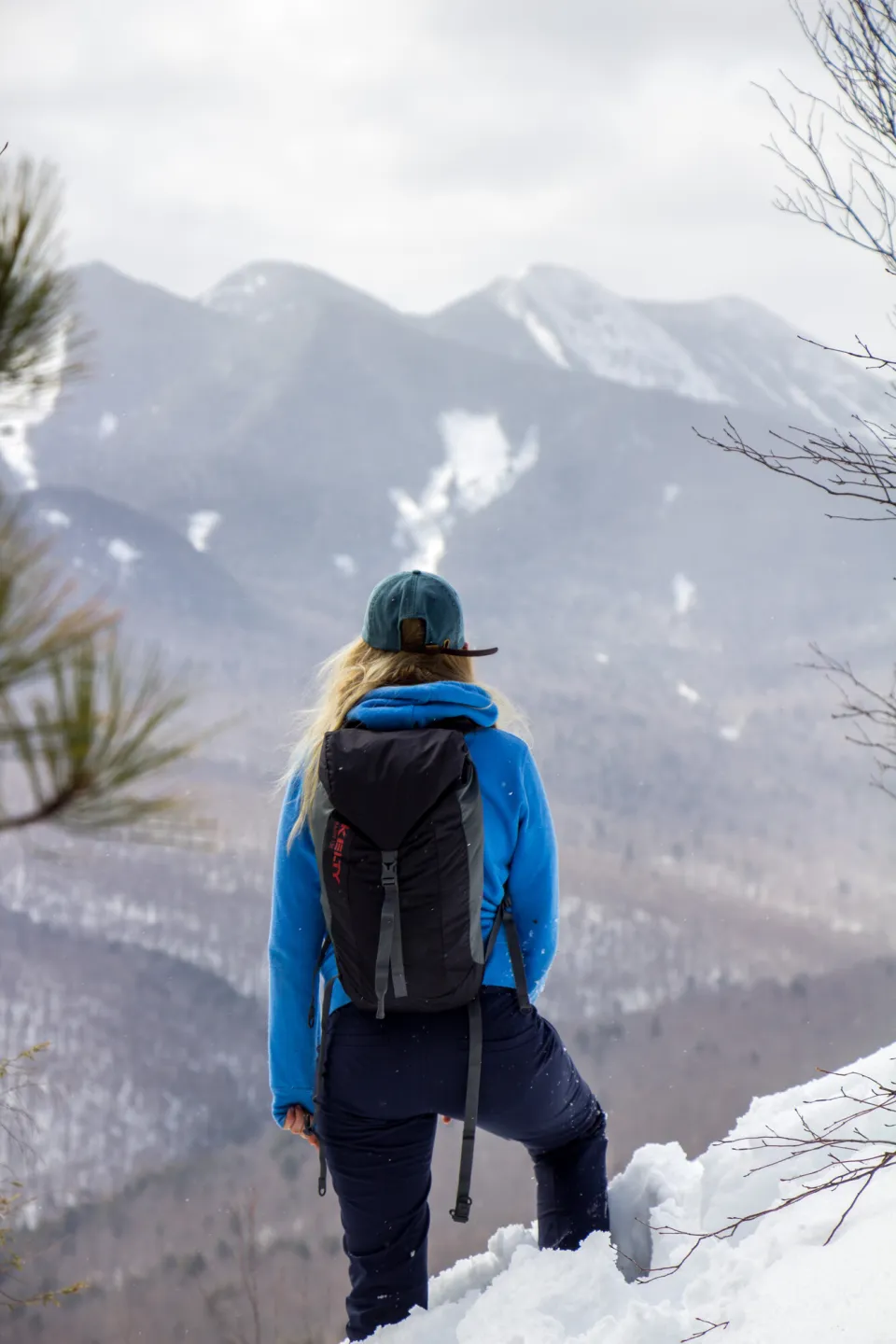 A woman standing at the summit of a winter hike.
