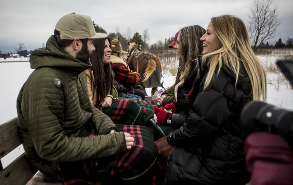 A group of friends on a horse drawn sleigh ride