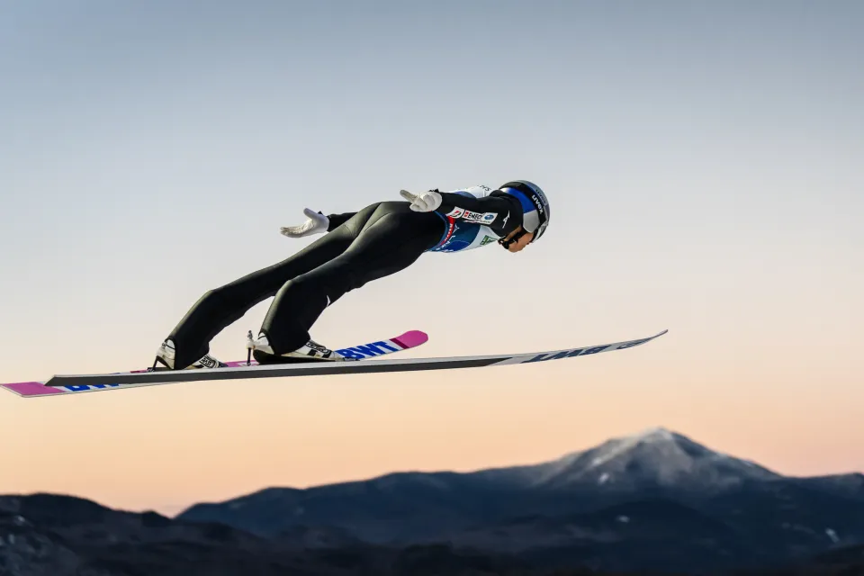 A skier jumping with mountain views.