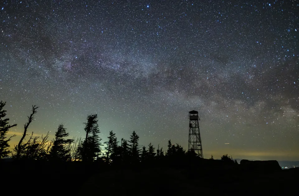 A fire tower at night with stars above.