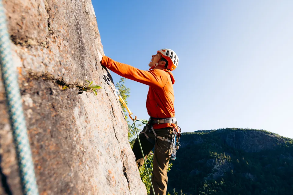 A man climbs a mountain side. 
