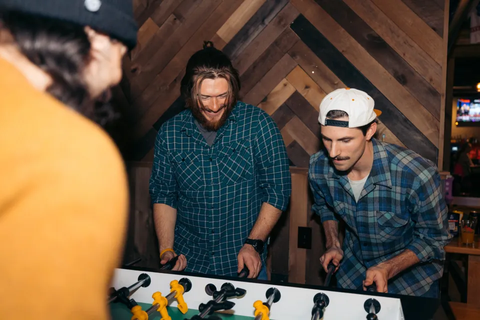 Friends play foosball together. 